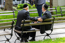 Unidentfied Jewish Men Wearing Kippah Talking In A Public Bench In Financial District Of New York