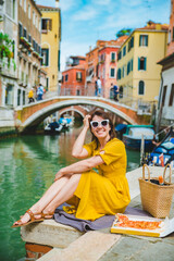 Wall Mural - woman sitting on pond with view of venice canal eating pizza