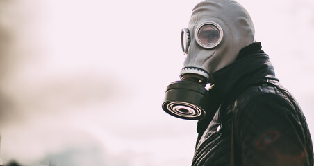 Wall Mural - casual young man in a gas mask standing on the street in an empty city