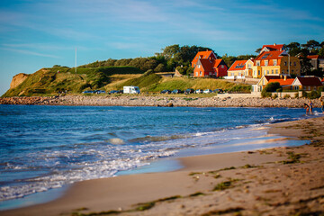 Beautiful Houses in typical yellow color on the beach with sea view during colorful sunset. Denmark, North Sea