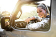 © elnariz - Cheerful smiling beautiful female on an adventure road trip, traveller on holiday, sunlight sunset coming through windshield