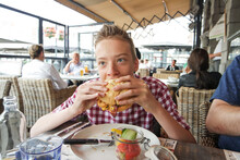 Close-up Of Teenage Boy Eating Burger At Restaurant