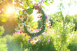 Beautiful floral wreath hanging on tree, sunny meadow natural background. floral traditional decor for Summer Solstice Day, Midsummer holiday. Witch tradition, wiccan ritual. Litha sabbat