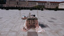 A Table In Front Of A Castle. On The Table Are Arranged Pink Flowers, Candles And A Bottle Of Champagne And Tasty Strawberries.