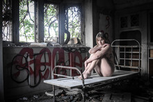 Full Length Of Naked Woman Sitting On Bed In Abandoned Room