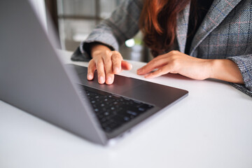 Closeup image of a woman working and typing on laptop computer keyboard on wooden table