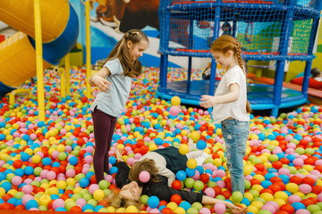 Wall Mural - Children with mother lying among colorful balls