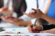 © H_Ko - Close up of woman writing notes in her notebook while sitting near colleagues in the office