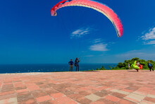 People With Parachute By Sea Against Blue Sky