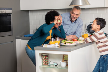 Smiling mixed race family with they son standing in the kitchen preparing sandwich for breakfast at home.