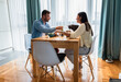© Zoran Zeremski - Young couple eating salad while sitting at a table at home.