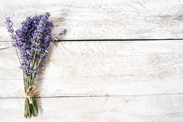 A fresh bouquet of lilac lavender tied with twine lies on a light wooden background. Beautiful bouquet of purple wildflowers on a vintage background. Free space for text. Top view