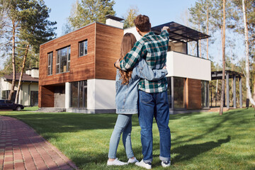 Young man hugging his girlfriend against new home