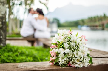 Wall Mural - Shallow focus shot of a couple sitting on a bench outdoors with flowers on the front