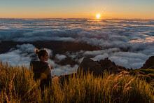 Woman On Top Of A Summit Watching The Sunrise Over The Fluffy Clouds	
