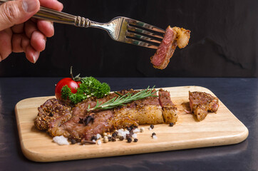 Fresh rare  striploin beef portion steak medium grill with seasoning , herb and spice on wood board and black background.