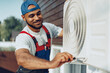 © fotofabrika - Young black man repairman checking an outside air conditioner unit