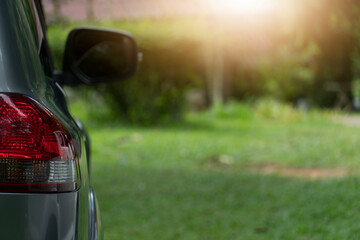 Side view of the car tail light. Parked on a beautiful green lawn For tourism or leisure travel.