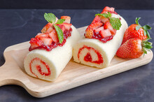 Delicious Home Made Cake Roll With Strawberry Marmalade Jam In Japanese Style  On A Wood Plate With Topping  Fresh Strawberry , Strawberry Marmalade Jam And Mint. Tasty Dessert.