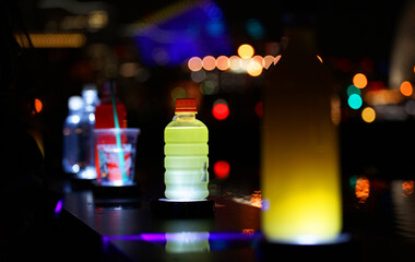 Wall Mural - Bottle of the drink lighted up by the colorful light on the table of the night room