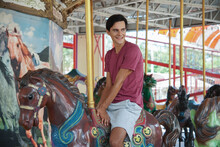 Happy Caucasian Young Handsome Man On Merry Go Round At The Amusement Park