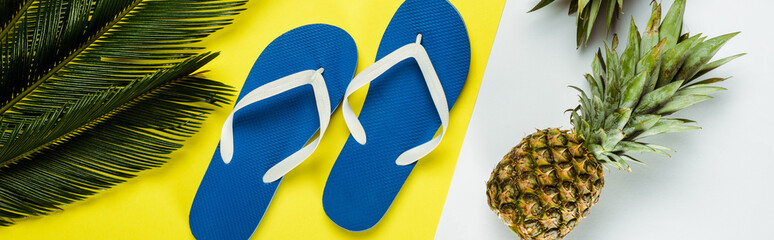 Sticker - top view of green palm leaves, pineapples, blue flip flops on white and yellow background, panoramic shot