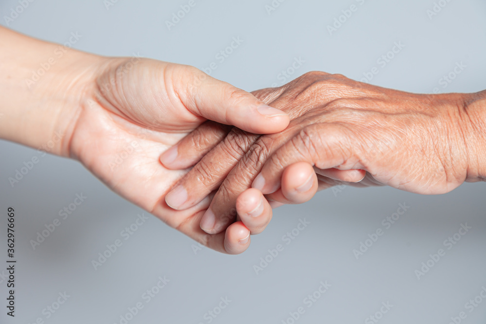 Old and young holding hands on white background . Close-up of tender ...