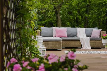 Wall Mural - Pastel pink pillows on grey sofa in green garden with wooden terrace