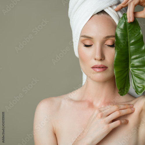 Fotomural A beautiful girl with a towel on her head holds a green leaf in her hands