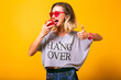 Studio image of young hipster woman eating apple and showing ok gesture, healthy lunch, vegan food.