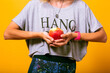 Woman at yours casual outfit holding apple, vegetarian lifestyle, yellow background.