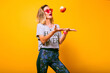 Young woman in bright sportive outfit playing with apple, healthy lifestyle, bright colors.