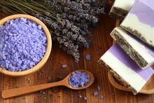 Sea Salt With Lavender In A Bamboo Bowl, Soap Made From Lavender, Olive Oil And Cocoa Butter On A Bamboo Plate And Dried Lavender Flowers Are Located On A Brown Wooden Table. Closeup.