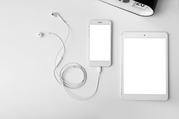 Modern tablet computer with mobile phone and earphones on table in room