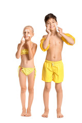 Wall Mural - Little children with sun protection cream on their faces against white background