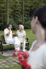 Wall Mural - Senior man talking on the phone with senior woman sitting beside him, woman holding a bouquet of flowers looking at them