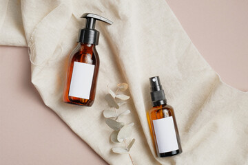 Wall Mural - amber glass cosmetic bottles set with towel and eucalyptus leaves on beige background. beauty produc