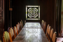 Wooden Tables And Chairs Opposite A Carved Window With Sunlight At A Buddhist Temple, Da Nang, Vietnam