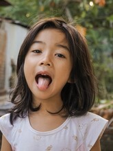 Portrait Of Cute Girl Sticking Out Tongue While Standing Outdoors