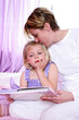 © ImageHit - A woman sitting on the bed kissing her daughter's head