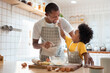 © eggeeggjiew - African Father and son enjoying during bake cookies at home together.