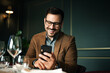 © bnenin - Cheerful man using smart phone in fancy restaurant, portrait, close-up.