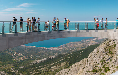 Tourists walking accross the newly built skywalk on Biokovo mountain. Wide view from the entrance, towns and the sea visible in far distance