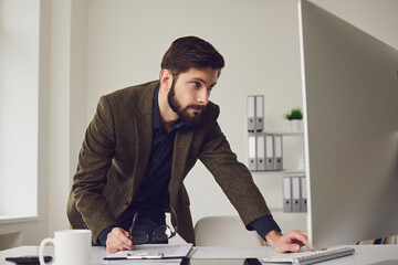 Businessman works at the computer at the table in the workplace in the office