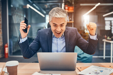 Happy businessman in suit looking at laptop excited by good news online