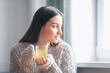 © VERSUSstudio - Beautiful woman drinking morning tea behind window