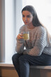 © VERSUSstudio - Beautiful woman drinking morning tea behind window
