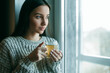 © VERSUSstudio - Beautiful woman drinking morning tea behind window