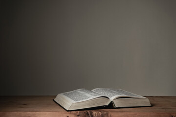 Open Holy Bible on a red wooden table and white wall background. Religion concept.