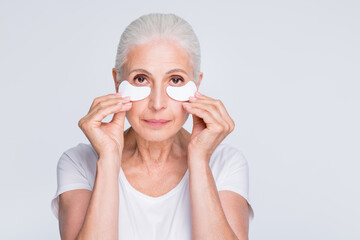 Sticker - Close up photo of charming grandmother applying gel holding cotton pad wearing stylish trendy t-shirt isolated over white background